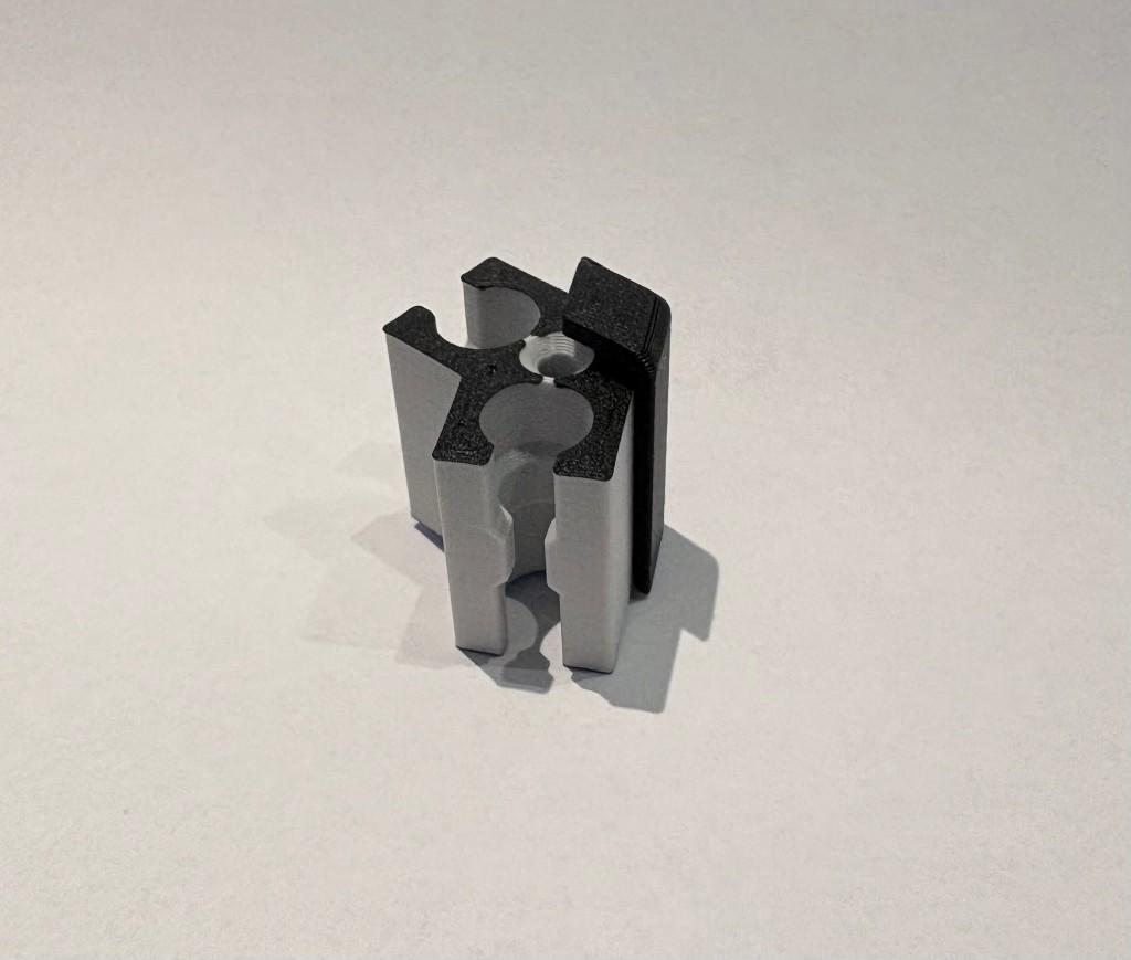 2-weg connector van lichtgrijs 3D-printmateriaal met zwarte bovenzijde, verticaal staand met twee halfronde gleuven voor de structuur