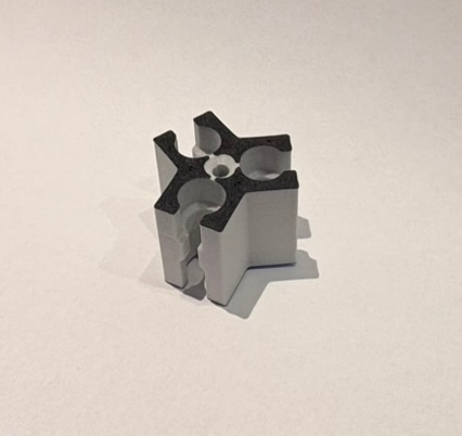 3-weg connector van lichtgrijs 3D-printmateriaal met zwarte bovenzijde en drie armen met halfronde gleuven